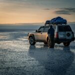 couple standing by a jeep in wet flat landscape